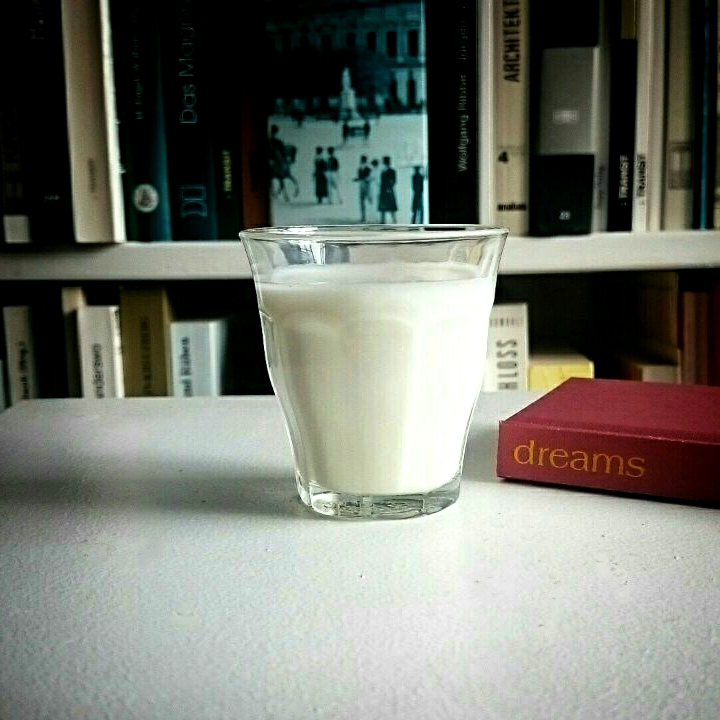 Ein Glas Milch neben einem kleinen Buch mit dem Titel "Dreams"