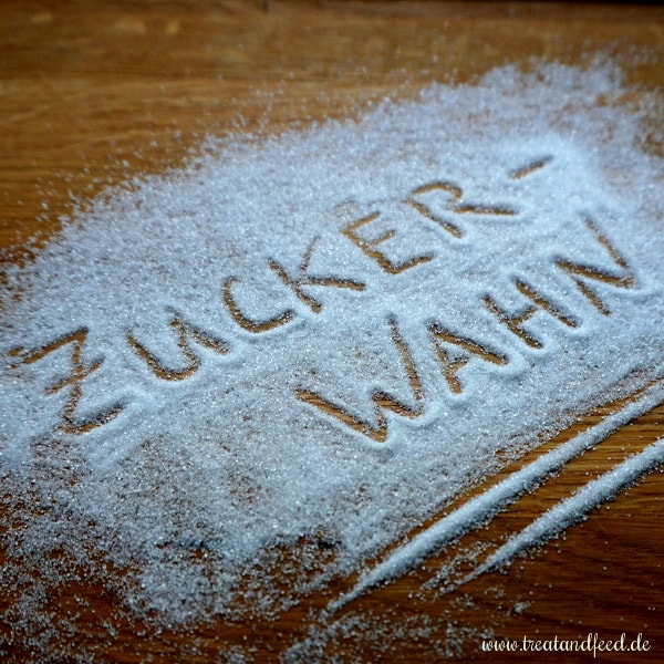 Das Wort "Zuckerwahn" eingeritzt auf einer dünnen Schicht Zucker.